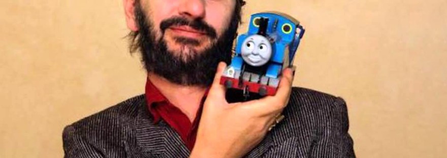 Image of Ringo Starr wearing a conductor hat, winking, and holding up a Thomas the Tank Engine toy against a beige background